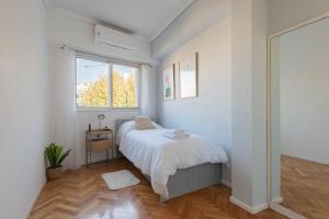 ein weißes Schlafzimmer mit einem Bett und einem Fenster in der Unterkunft Fliphaus 3 De Febrero 700 - 2 Bd Embassies Area in Buenos Aires
