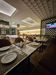 a dining room with tables and chairs and a television at Atithi House in Greater Noida