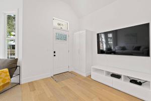 a white living room with a large tv on the wall at Haven Tiny House - Heated Pool - Walk To Downtown in St. Augustine