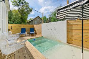 a swimming pool with chairs and an umbrella on a patio at Haven Tiny House - Heated Pool - Walk To Downtown in St. Augustine