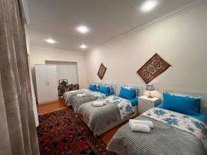 three beds in a room with blue pillows at Nuray's House in Sheki