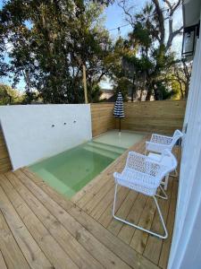 a pool with two chairs and a table on a wooden deck at Haven Tiny House - Heated Pool - Walk To Downtown in Saint Augustine