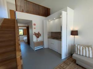una cucina con armadi bianchi e una scala in una stanza di Ocean & Countryside Apartments a Encarnação
