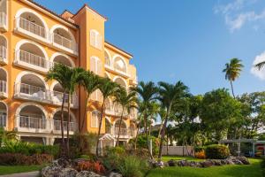 a yellow building with palm trees in front of it at St Peter's Bay Luxury Resort and Residencies in Saint Peter