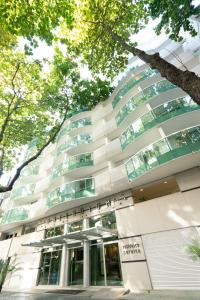 a white building with a tree in front of it at Promenade Palladium Leblon in Rio de Janeiro