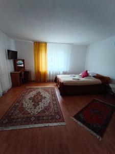 ein Schlafzimmer mit einem Bett und einem Teppich auf einem Holzboden in der Unterkunft Casa Dyasof in Rohia