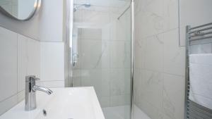 a white bathroom with a shower and a sink at Queens Large 2 BDR & 1 BDR Apartments by Belfast City Breaks in Belfast