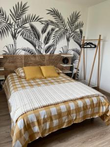 ein Schlafzimmer mit einem Bett und einem Wandbild von Palmen in der Unterkunft Gîte du blé normand in Corny
