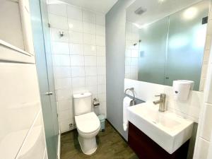 een badkamer met een toilet, een wastafel en een spiegel bij Olea's Home Las Condes in Santiago