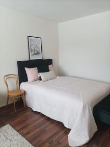 a bedroom with a large white bed and a chair at Viihtyisä ja valoisa yksiö keskustan läheisyydessä in Heinola