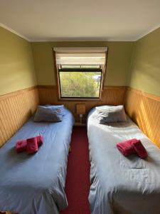two beds in a small room with a window at Cabañas Lago Tyndall in Torres del Paine