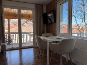 uma sala de jantar com mesa, cadeiras e janelas em Black Cat Apartment em Veliko Tarnovo