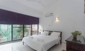 a bedroom with a white bed and a large window at 519@jamtree in Colombo