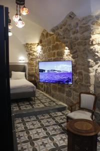 1 dormitorio con 1 cama y TV en una pared de piedra en Shafika house, en Acre