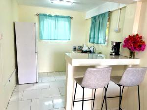 una cocina con 2 taburetes y una cocina con cortinas azules en Happy-Nest (First floor), en Marigot