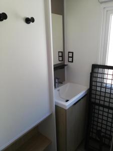 La salle de bains est pourvue d'un lavabo et d'un miroir. dans l'établissement Mobilhome Clim Télé La Falaise 4 étoiles, à Narbonne