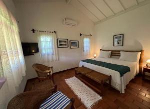 a bedroom with a bed and a chair in it at Pousada Villa Cumuru in Cumuruxatiba