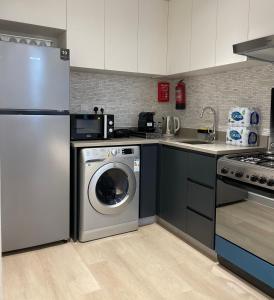 a kitchen with a washing machine and a sink at 1 BR Luxury Apt by AJ Aljada in Sharjah