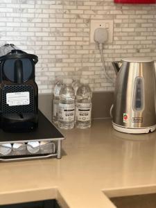 a kitchen counter with a coffee maker and water bottles at 1 BR Luxury Apt by AJ Aljada in Sharjah