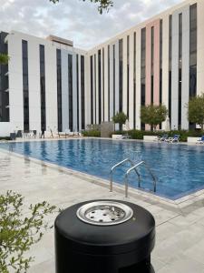 een groot zwembad met een gebouw op de achtergrond bij 1 BR Luxury Apt by AJ Aljada in Sharjah