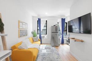 a living room with a yellow couch and a tv at 69-2C Brand New PRIME Lower East Side 1br Apt in New York