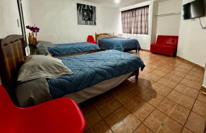 a room with two beds and a red chair at CASA ENTERA PURA VIDA! in Ciudad Hidalgo