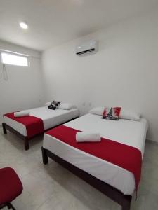 2 camas en una habitación blanca con sábanas rojas y blancas en Hotel Cermar Plaza, en La Barca
