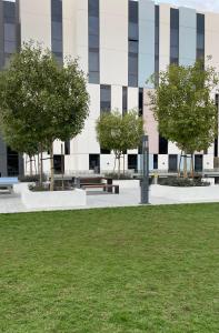 a building with a bench and trees in front of it at 1 BR Luxury Apt by AJ Aljada in Sharjah