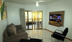 sala de estar con sofá y TV de pantalla plana en 1029 - Apartamento no centro de Bombinhas - Residencial estrela do mar 2 104 A, en Bombinhas