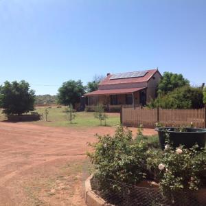 uma casa com uma cerca em frente a uma estrada de terra em Gum Paddock Country Cottage em Broken Hill