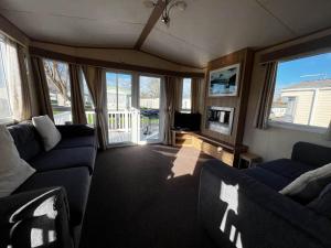 a living room with two blue couches and a tv at Lovely Caravan With Decking At Cherry Tree Holiday Park In Norfolk Ref 70528c in Great Yarmouth