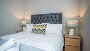 a bedroom with a large white bed with two lamps at Queens Large 2 BDR & 1 BDR Apartments by Belfast City Breaks in Belfast