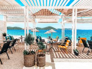 eine Terrasse mit Stühlen, Tischen und Meerblick in der Unterkunft Buqez Eco Resort - Beach Villa 22 in Drage