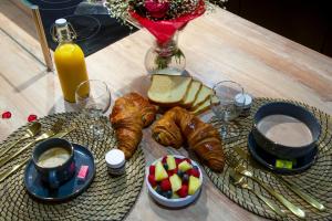 stół ze śniadaniem obejmującym rogaliki, chleb i sok w obiekcie La prestigieuse Sauna Balnéo Ciné w mieście Roannes-Saint-Mary