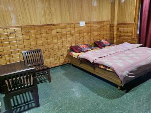 a bedroom with a bed and a chair in it at Shanti guest house chojh in Kasol