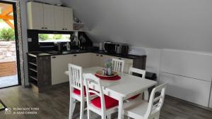 Apartmán na Šumavě في فيمبيرك: مطبخ مع طاولة بيضاء وكراسي في غرفة