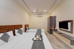 Hotel Bellwood Grand Near Delhi IGI Airport في نيودلهي: غرفة فندقية بسرير وتلفزيون بشاشة مسطحة