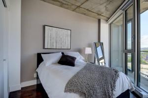 Schlafzimmer mit einem Bett mit weißer Bettwäsche und einem Fenster in der Unterkunft Les Immeubles Charlevoix - 760-212 in Québec