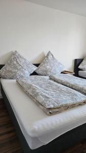 een bed met witte lakens en kussens erop bij City Apartment Kehl in Kehl am Rhein