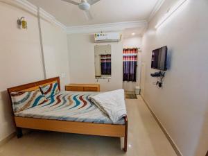 HK Inn في ماندفي: غرفة نوم صغيرة بها سرير وتلفزيون