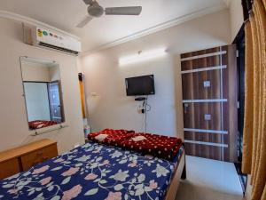 um pequeno quarto com uma cama e uma televisão em HK Inn em Mandvi