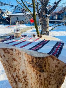 een picknicktafel met een fles wijn bovenop een boomstronk bij Casa Cataleya in Bucşoaia