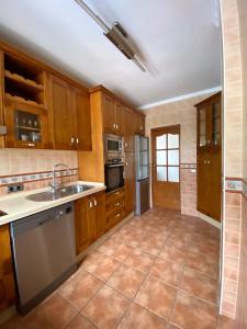 a kitchen with wooden cabinets and stainless steel appliances at Chalet La Noria in Nerja