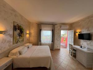 a bedroom with a bed and a desk and a television at Borgo di Santa Barbara in Santa Domenica