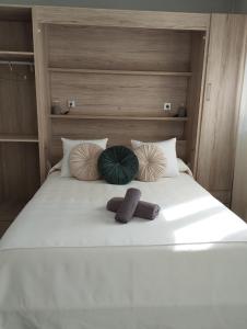 a bed with three pillows and towels on it at Apartamento La Fuente 27 in Tomares