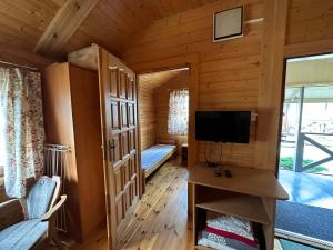 a room with a bed and a tv in a cabin at Domki Rodzinne Jantar in Bobolin
