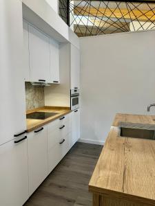 a kitchen with white cabinets and a wooden table at Apartamentos centro I.II in El Barraco