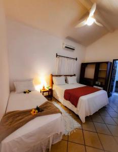 a bedroom with two beds and a table with a lamp at Pousada Villa Cumuru in Cumuruxatiba