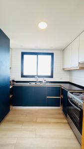 a kitchen with blue cabinets and a sink and a window at PH Duplex con Terraza y Asador en Microcentro in Santiago del Estero