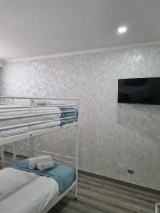 ein Schlafzimmer mit einem Etagenbett und einem TV an der Wand in der Unterkunft Mikaela Guest House in Odivelas